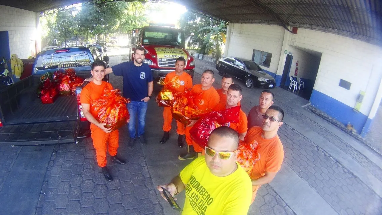 Personal del Cuerpo de Bomberos recibiendo donaciones junto a un camión de bomberos